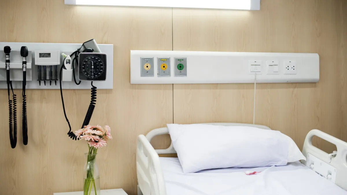 Katil hospital kosong dan peralatan perubatan di dinding