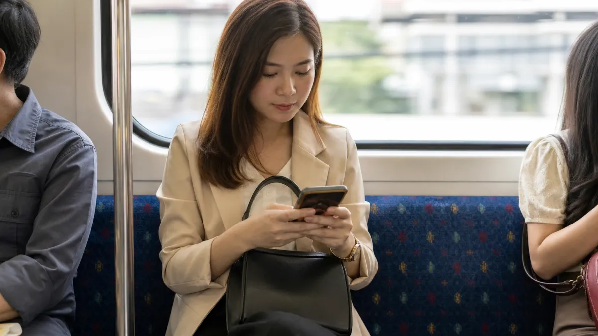 Wanita muda menyemak bayaran balik pinjaman di telefon dalam tren
